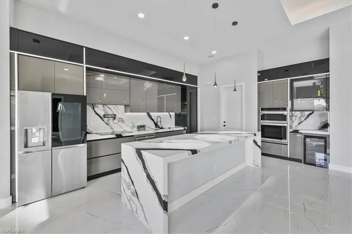 Kitchen with modern cabinets, stainless steel appliances, gray cabinetry, light marble finish floors, and recessed lighting