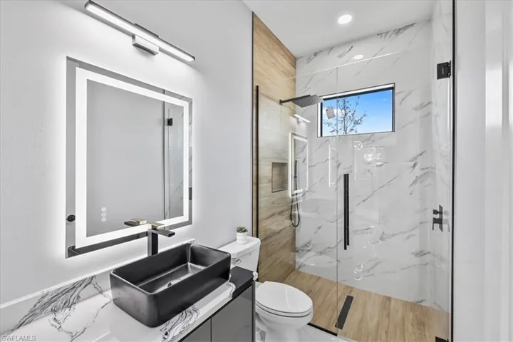 Bathroom featuring vanity, a marble finish shower, and recessed lighting
