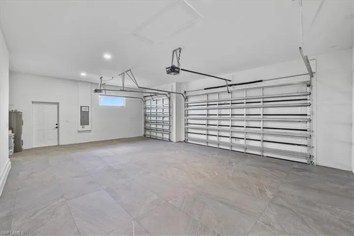 Garage with recessed lighting, electric water heater, electric panel, and a garage door opener