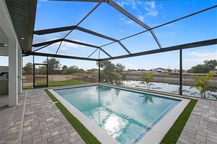 Swimming pool featuring a sunroom, a lanai, a patio, and a water view