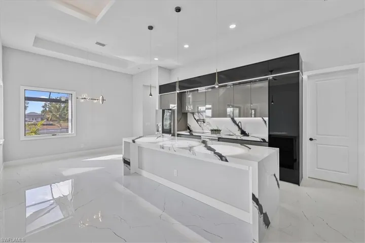 Kitchen featuring modern cabinets, hanging light fixtures, dark cabinetry, a center island with sink, and recessed lighting