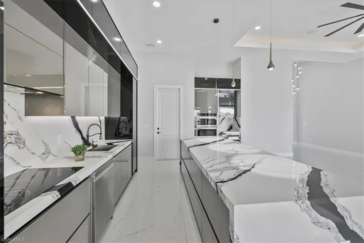 Kitchen featuring modern cabinets, light stone countertops, hanging light fixtures, recessed lighting, and stainless steel appliances
