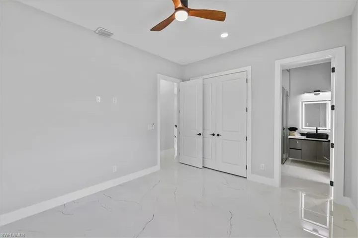 Unfurnished bedroom with light marble finish flooring, a closet, ceiling fan, recessed lighting, and ensuite bathroom