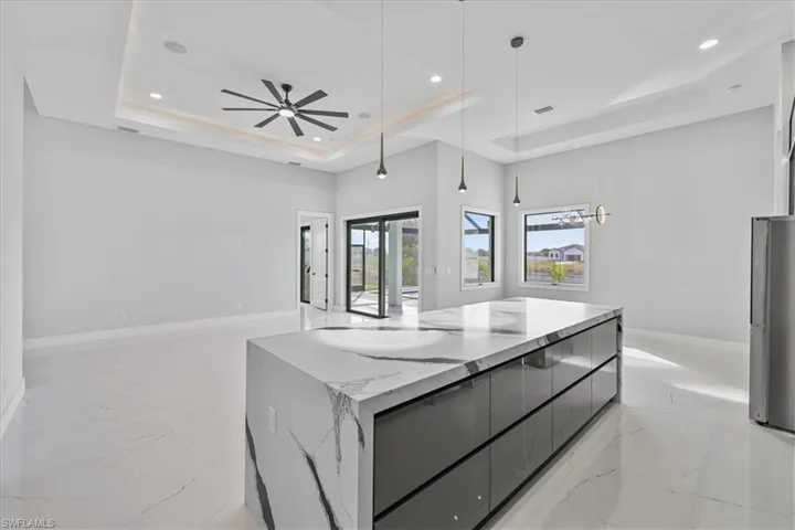 Kitchen featuring modern cabinets, hanging light fixtures, a tray ceiling, freestanding refrigerator, and recessed lighting