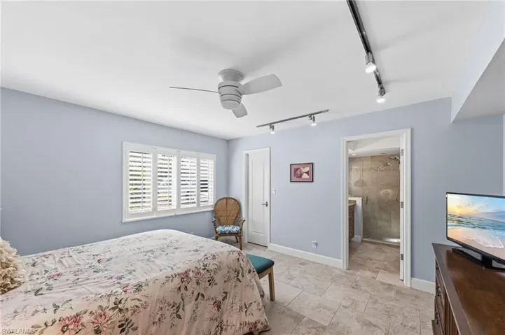 Bedroom with track lighting, a ceiling fan, and ensuite bathroom