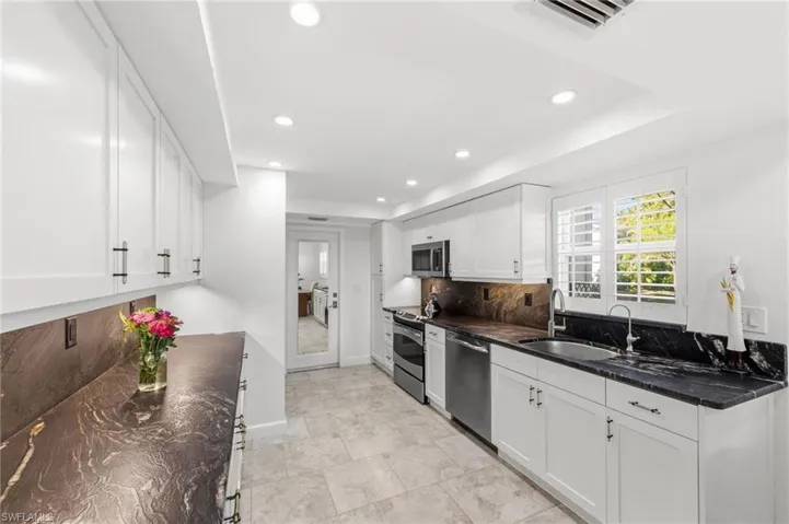 Kitchen with white cabinetry, tasteful backsplash, dark stone countertops, stainless steel appliances, and recessed lighting