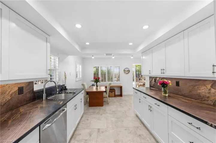 Kitchen with tasteful backsplash, a raised ceiling, stainless steel dishwasher, white cabinets, and recessed lighting