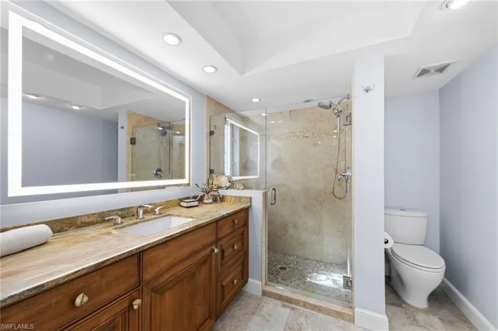 Bathroom with a shower stall, vanity, and recessed lighting