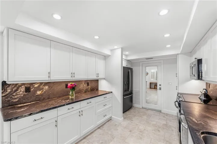 Kitchen featuring white cabinets, stainless steel appliances, recessed lighting, dark stone countertops, and backsplash