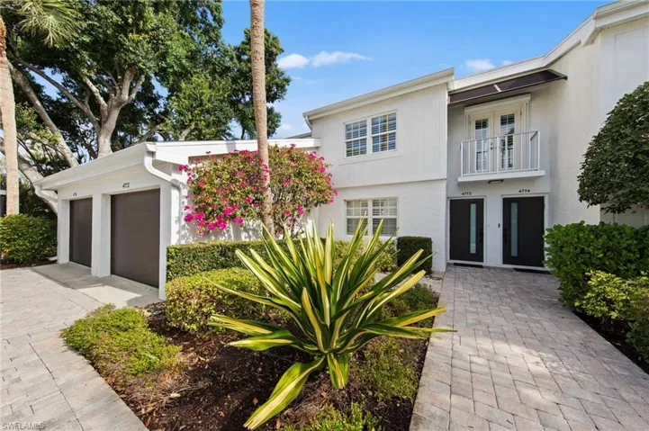 View of front of property featuring a balcony, an attached garage, stucco siding, and driveway