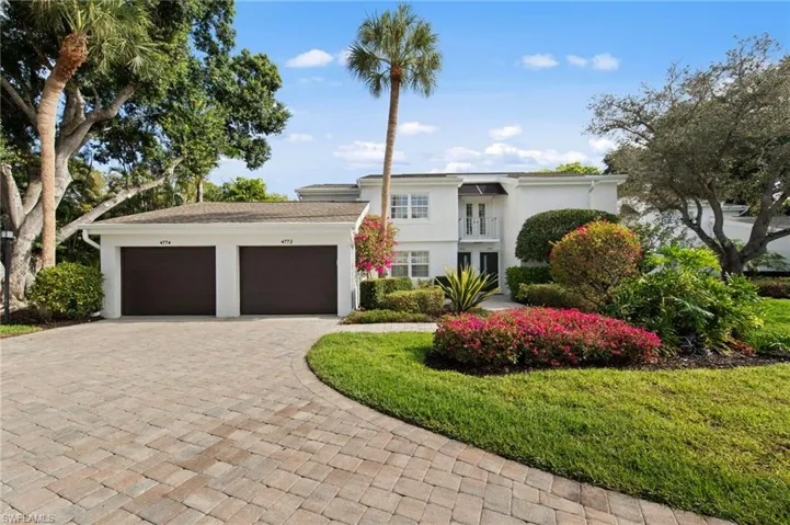 View of front of property featuring stucco siding, decorative driveway, an attached garage, and a front yard