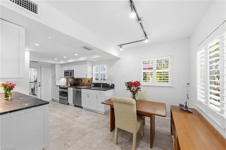 Kitchen featuring white cabinetry, rail lighting, stainless steel appliances, and tasteful backsplash