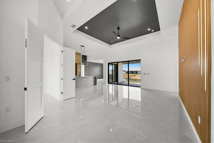 Spare room featuring a raised ceiling, light marble finish floors, and ceiling fan