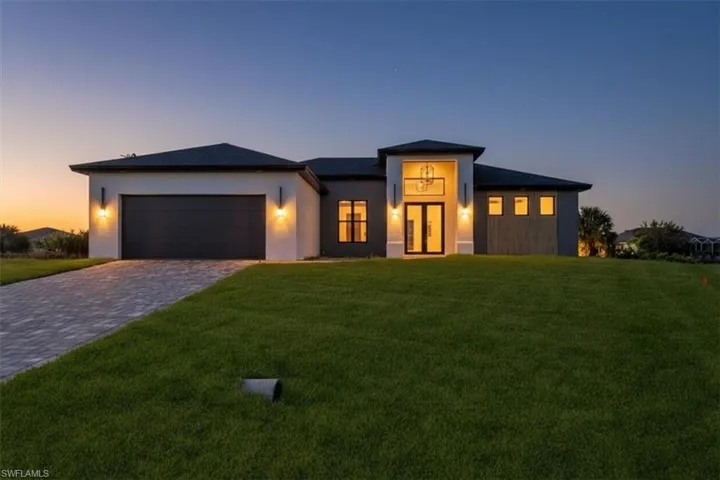 Prairie-style home with a yard, decorative driveway, a garage, and stucco siding