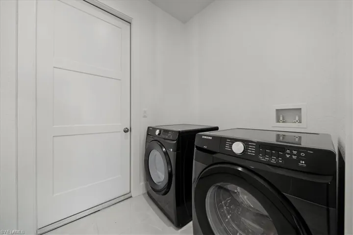Washroom with tile patterned flooring and washing machine and dryer