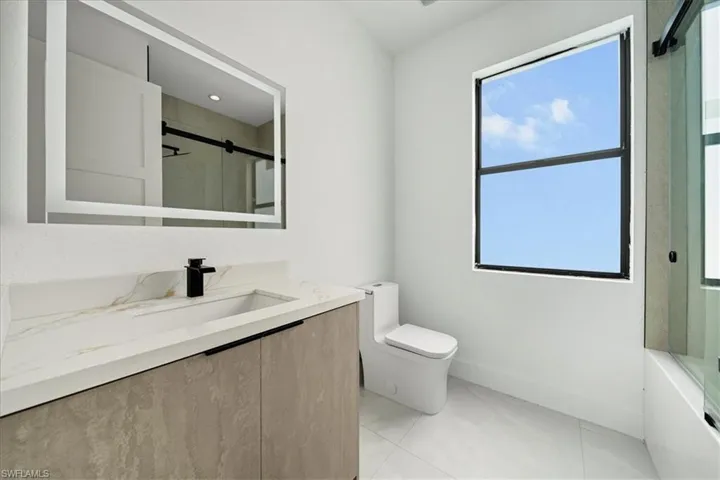 Full bath featuring vanity, light tile patterned floors, and shower / bath combination with glass door