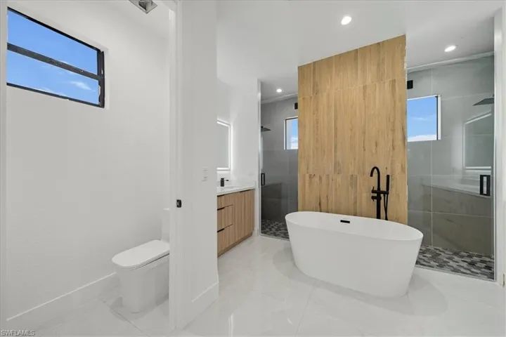 Full bath featuring vanity, a stall shower, a soaking tub, recessed lighting, and light tile patterned floors