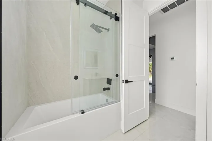 Full bath with enclosed tub / shower combo and tile patterned flooring