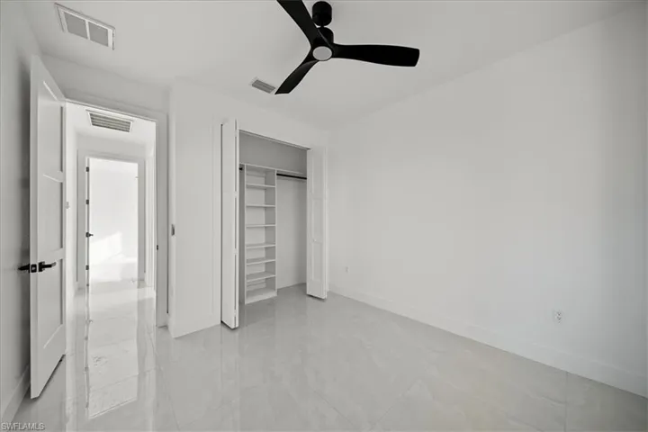 Unfurnished bedroom with ceiling fan and a closet