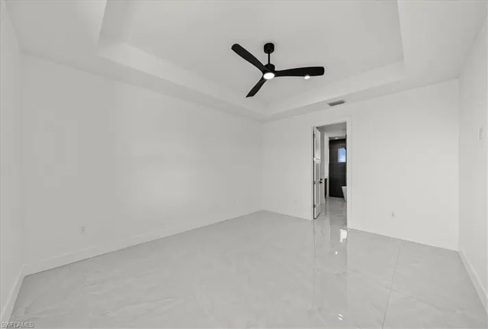 Unfurnished room with a tray ceiling and ceiling fan