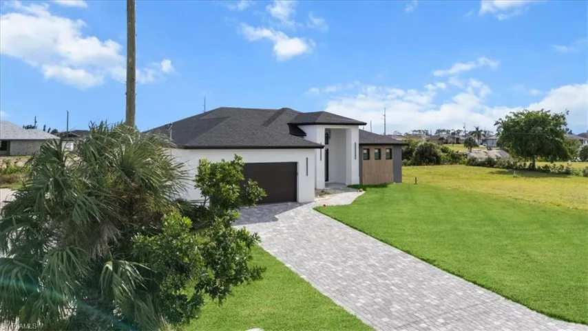 View of front of house featuring a front yard, a garage, stucco siding, decorative driveway, and a shingled roof