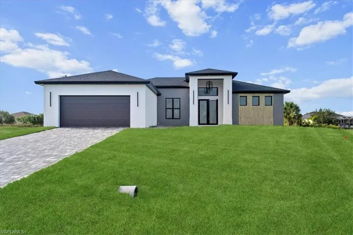 View of front of property featuring a front yard, stucco siding, decorative driveway, and a garage