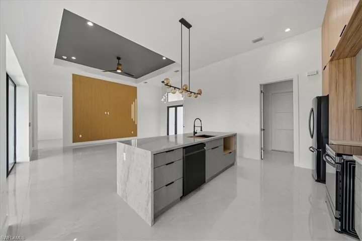 Kitchen featuring a tray ceiling, modern cabinets, decorative light fixtures, light stone countertops, and recessed lighting