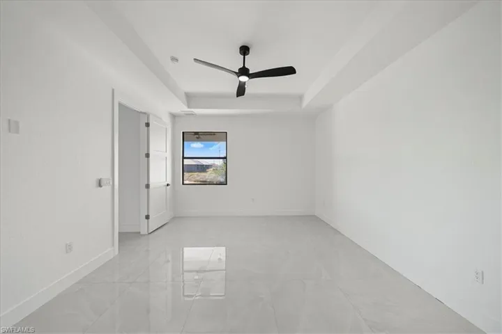 Empty room featuring ceiling fan and a tray ceiling