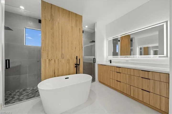 Full bathroom with a stall shower, a soaking tub, vanity, tile walls, and recessed lighting