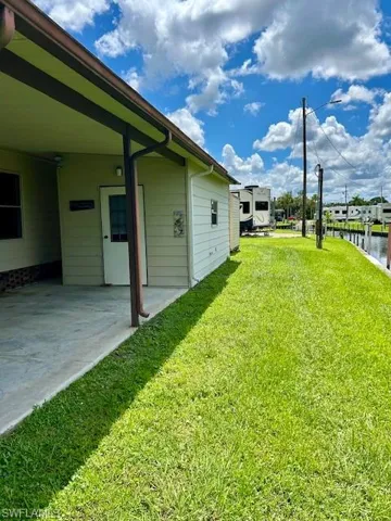 View of green lawn featuring a patio area and a water view