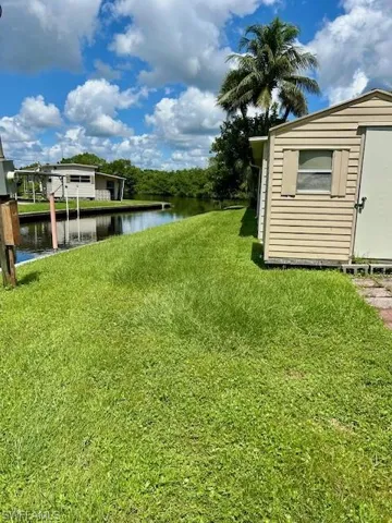 View of grassy yard featuring a water view and a shed