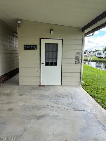 Property entrance featuring a patio area, a water view, and a yard