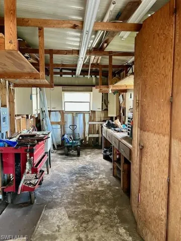 Miscellaneous room featuring concrete flooring, electric panel, and a workshop area