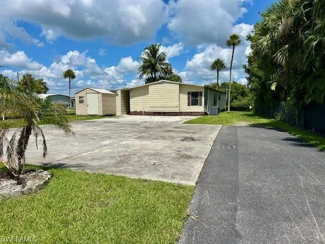 Manufactured / mobile home with a shed, a front yard, and driveway