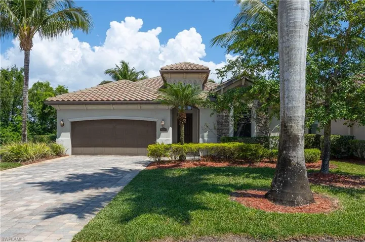 Mediterranean / spanish house featuring a front yard, stucco siding, a tiled roof, decorative driveway, and a garage