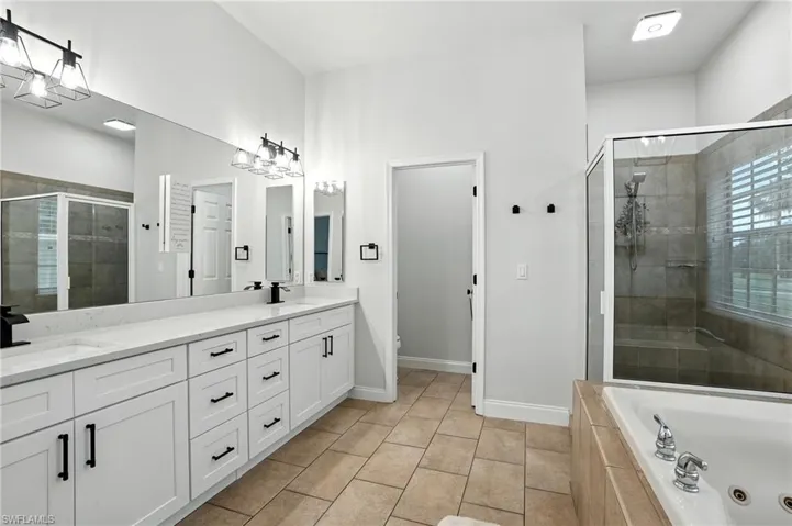 Bathroom with a stall shower, a jetted tub, double vanity, and light tile patterned flooring