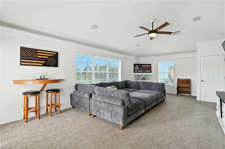 Living area featuring light carpet and a ceiling fan