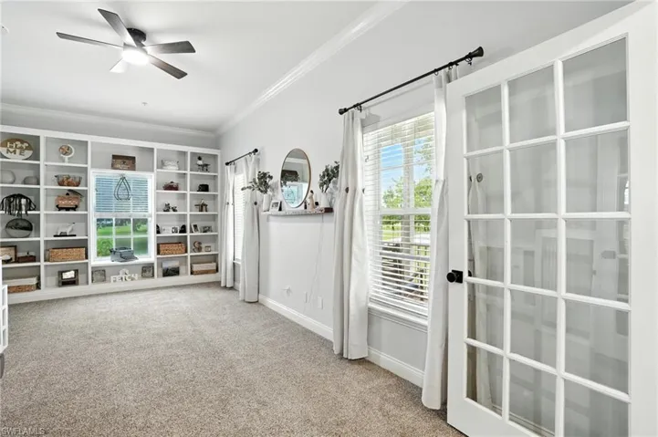Doorway featuring carpet floors, ornamental molding, and a ceiling fan