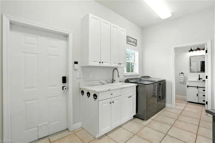 Laundry room with separate washer and dryer, cabinet space, and light tile patterned flooring