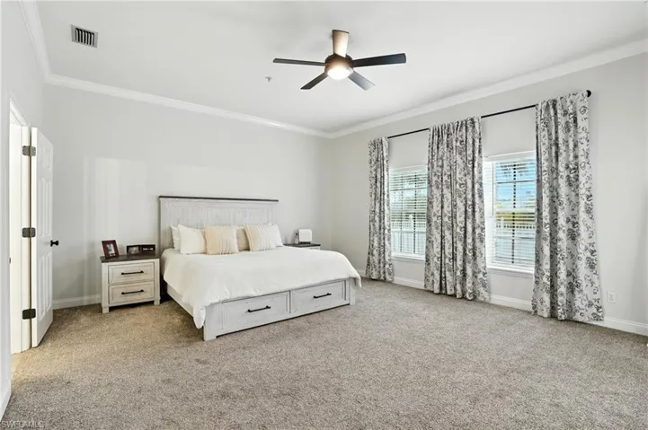 Bedroom with ornamental molding, light carpet, and ceiling fan