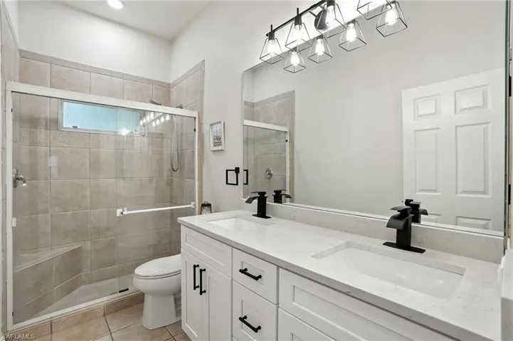 Full bathroom featuring a stall shower, double vanity, and light tile patterned flooring
