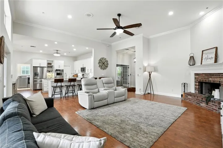 Living area featuring recessed lighting, ornamental molding, a fireplace, a ceiling fan, and dark wood-type flooring