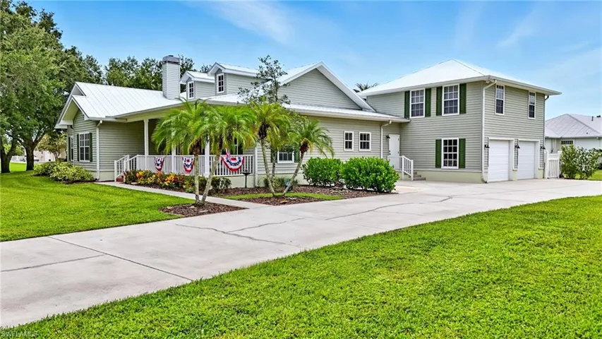 View of front facade with a front lawn, concrete driveway, covered porch, a chimney, and an attached garage
