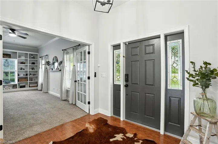 Carpeted entryway with wood finished floors and crown molding