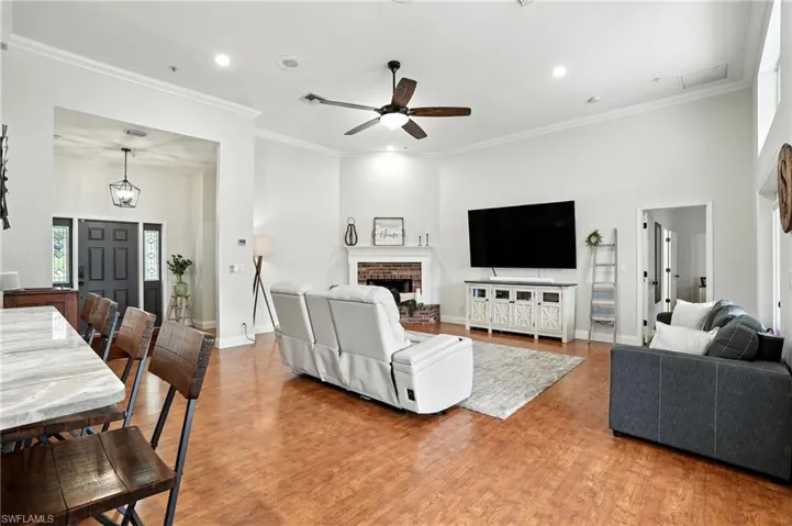 Living room featuring ornamental molding, light wood-style flooring, a fireplace, recessed lighting, and ceiling fan