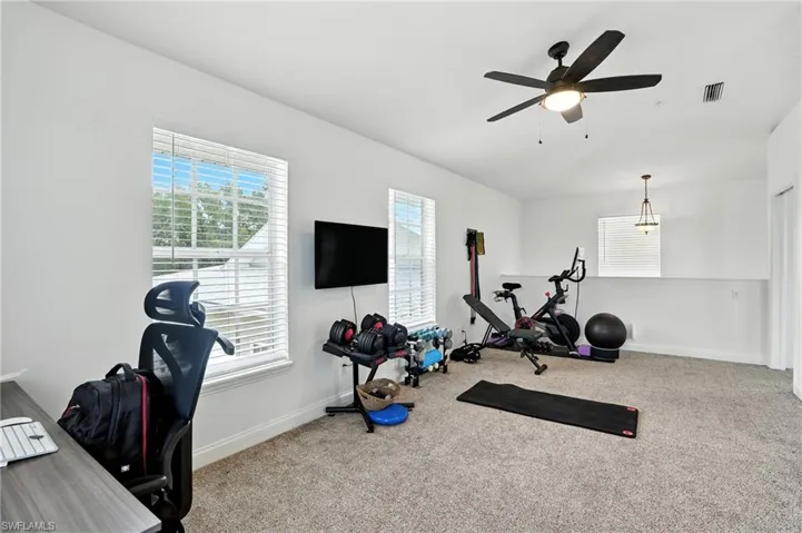 Workout area featuring light colored carpet and a ceiling fan