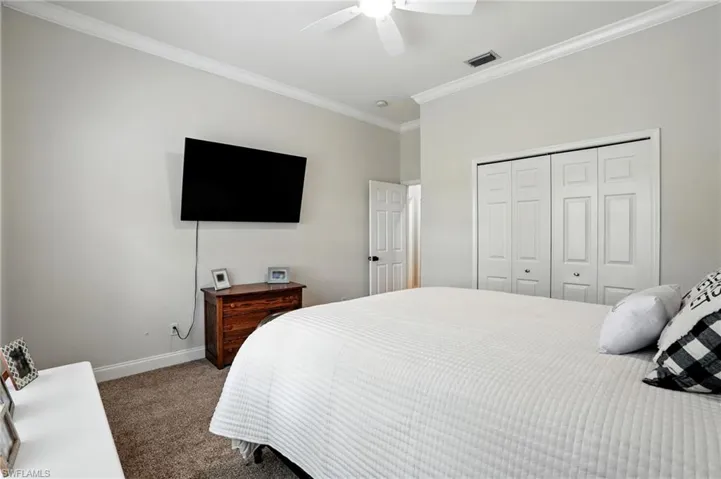 Carpeted bedroom with ornamental molding, a closet, and a ceiling fan