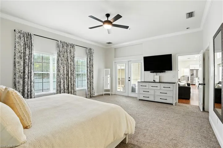 Bedroom featuring ornamental molding, light colored carpet, access to exterior, and ceiling fan