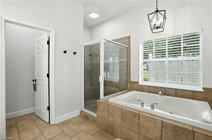 Bathroom featuring a stall shower, a garden tub, and light tile patterned flooring