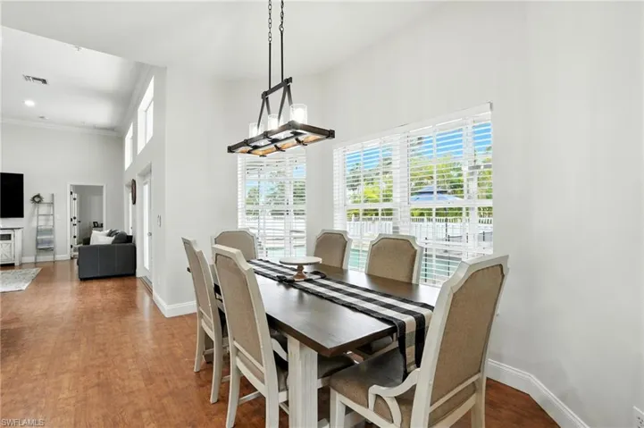 Dining room with dark wood-style floors, a towering ceiling, and crown molding